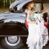 A bride in her wedding dress getting out of the car.