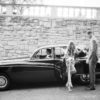 A woman in white dress standing next to a car.