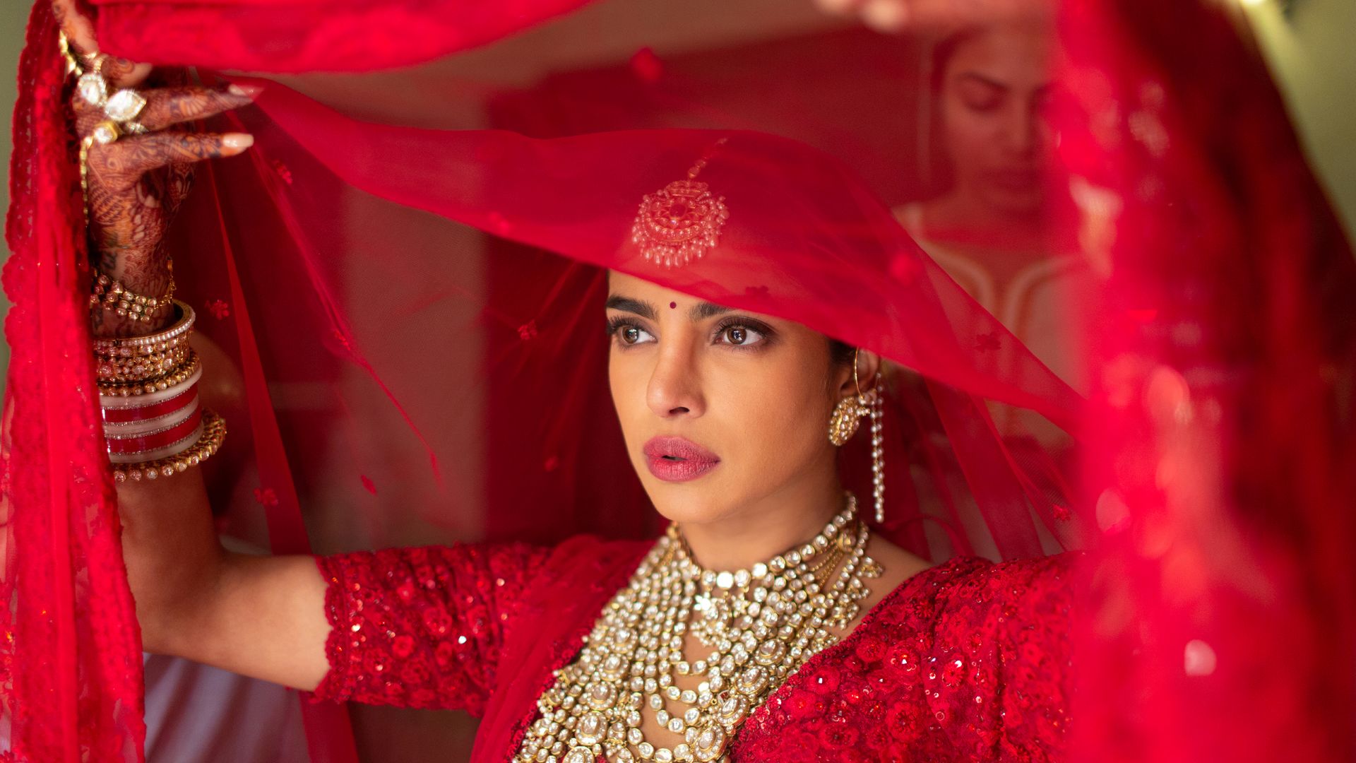 A woman in red is wearing a hat and jewelry.
